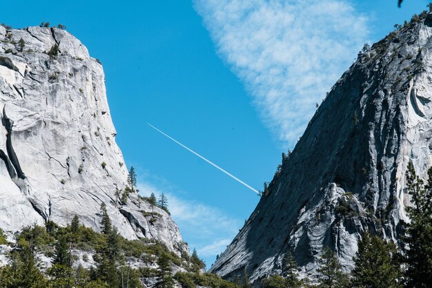 Foto vista degli alberi prima delle cime delle montagne sotto il cielo blu