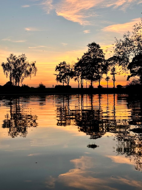 A view of trees that are reflected in the water and the sunset