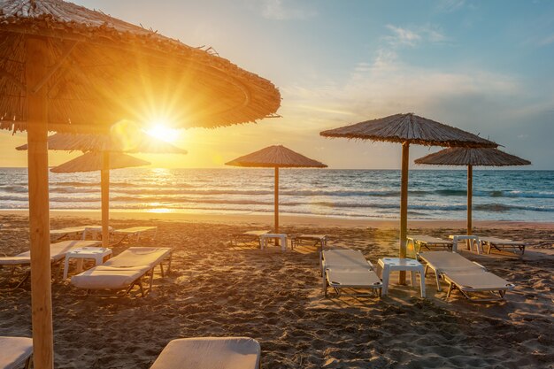 View of tropical beach with umbrellas during sunset