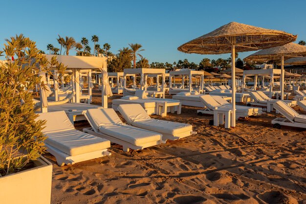 View of tropical beach with umbrelles during sunset Holiday vacation and travel concept