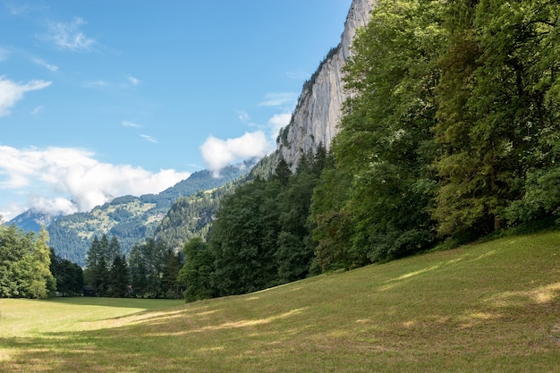 스위스, 유럽, 라우터브루넨(Lauterbrunnen) 시의 국립공원에 있는 폭포의 계곡을 보십시오. 여름 풍경, 햇살 날씨, 극적인 푸른 하늘과 화창한 날