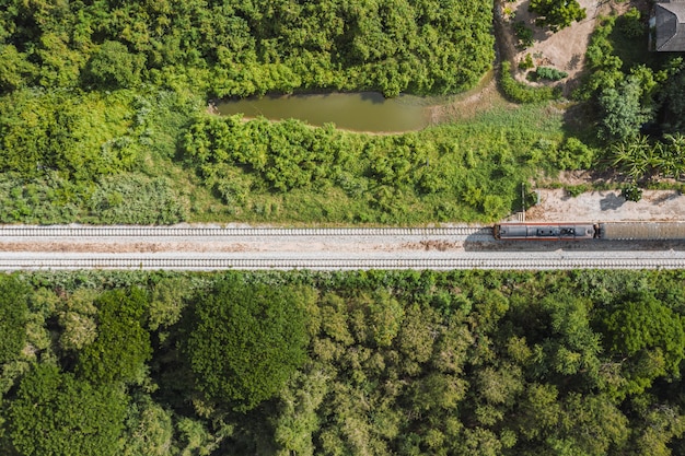 Above view, Vintage train driving on railway track in tropical forest at countryside