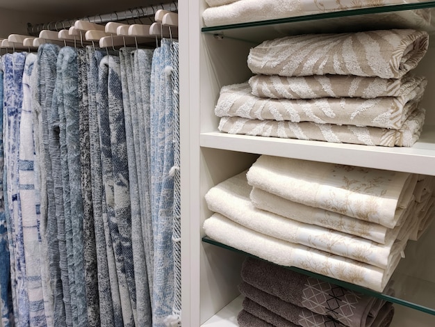 View of a wardrobe with woolen blankets hanging on hangers and terry towels on the shelves.