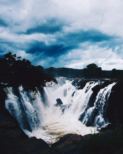 Photo view of waterfall against cloudy sky