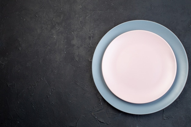 Above view of white and blue ceramic empty plates on black background with free space