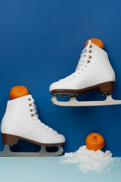 Photo view of white ice skates with tangerines and snow