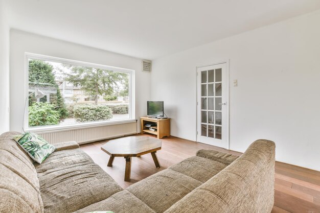 View of white living room in minimal style with television,sofa , wooden octagon table and a large window