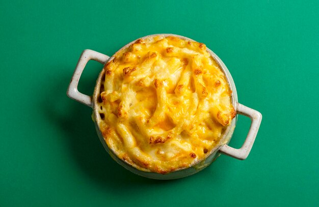 Above view with cooked mac and cheese in a ceramic tray isolated on a green colored background