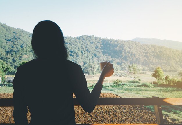 View a woman in the morning with the neat body is holding a cup of hot tea or coffee