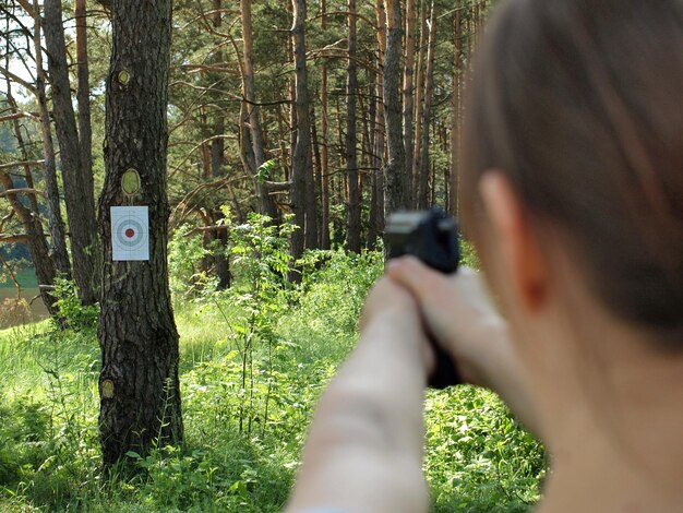 Foto vista di una donna che spara nella foresta