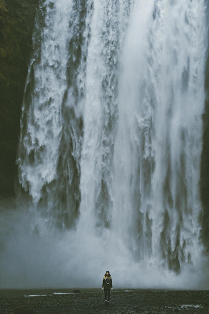 View of woman standing in front of waterfall