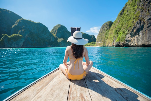 View of woman in swimsuit enjoying on thai traditional longtail Boat over beautiful mountain and ocean, Phi phi Islands, Thailand