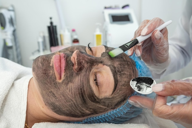 View of woman with cosmetic face mask lying on bed in spa center