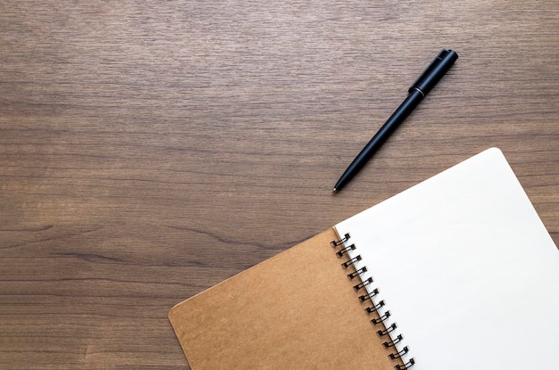 A view of a wooden desk from above with an open notebook