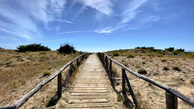 View of wooden footbridge on landscape against sky