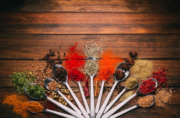 View of wooden table full of spices in spoons you can see the most popular condiments and seasoners