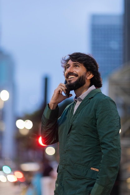 View of young man using a smartphone at night time with city view landscape in the background mobile phone technology urban concept high quality photo person