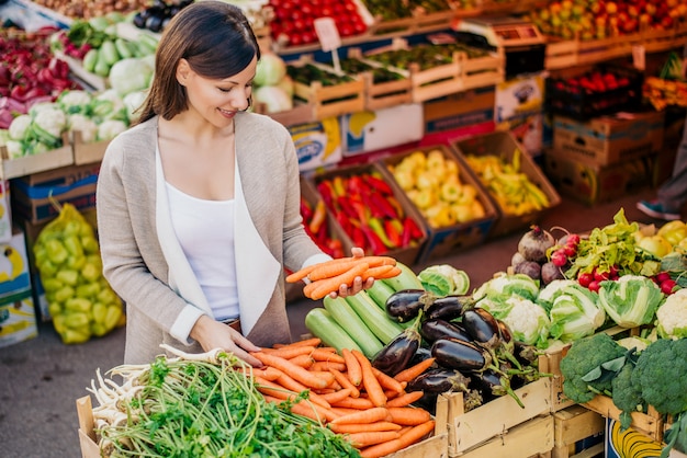 Mostra alla giovane donna comprare verdure al mercato.