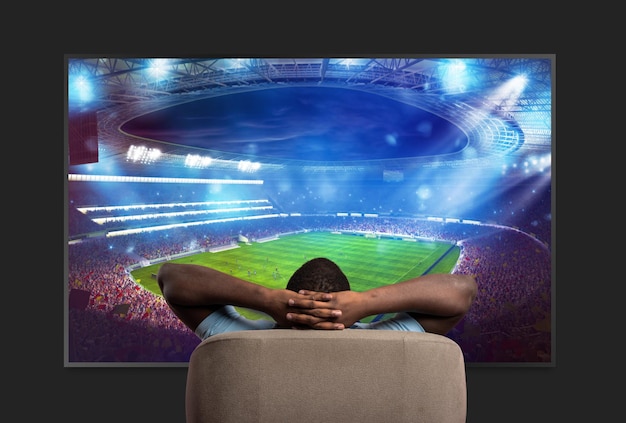 Foto spettatore davanti a un grande televisore rilassato sulla poltrona di casa a guardare una partita sportiva