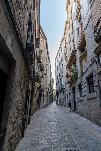 Views of the narrow streets of the old town of Girona with a woman.