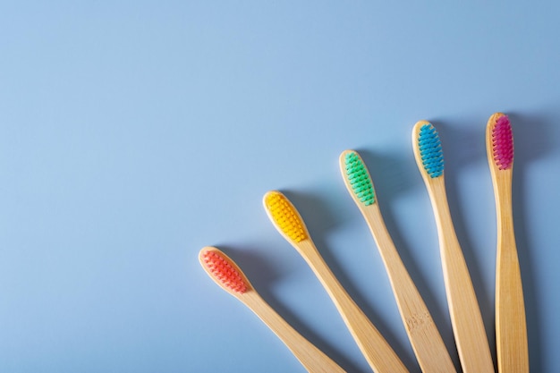 Vijf bamboe tandenborstels met veelkleurige borstelharen op een blauwe achtergrond