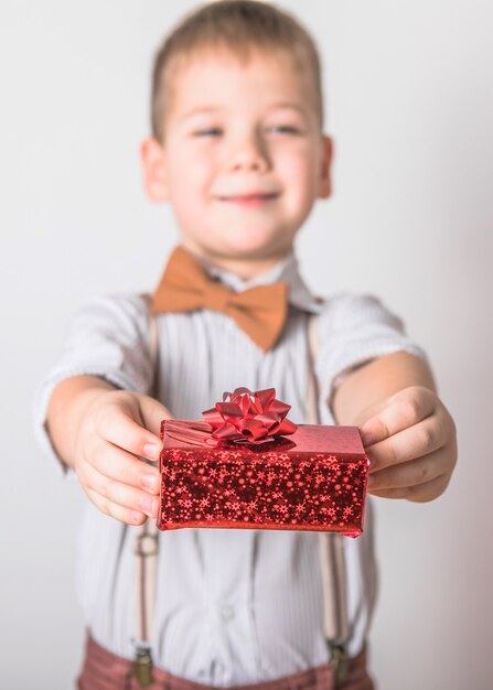 Vijf jaar oude glimlachende jongen geeft een rood cadeau