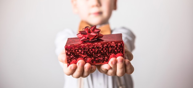 Vijf jaar oude glimlachende jongen geeft een rood cadeau