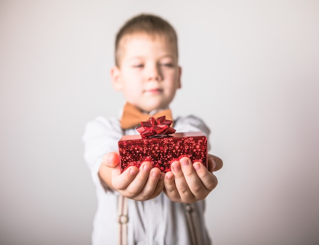 Vijf jaar oude glimlachende jongen geeft een rood cadeau