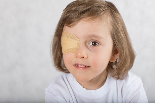 Vijf jaar oude jongen met één oog bedekt met oogkussentje en met een bril.