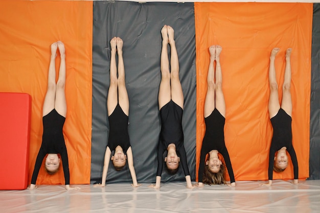 Vijf kleine meisjes die gymnastische bewegingen maken op een podium