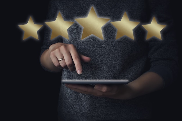 Vijf sterren service rating concept. Vrouw met een digitale tablet in handen met een 5 gouden sterren