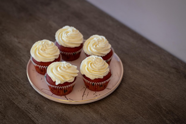 Vijf zelfgemaakte rood fluwelen cupcakes met roomkaas glazuur op een bord op houten tafel