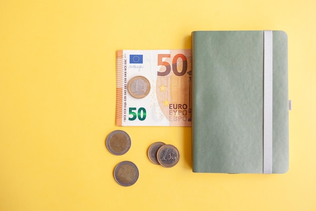 Vijftig eurobankbiljetten in een zwarte portemonnee op gele achtergrond