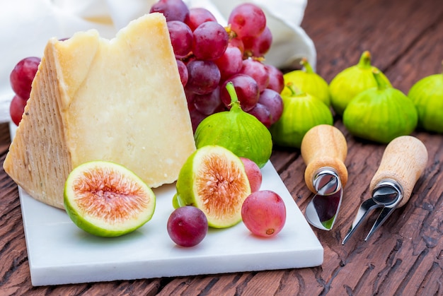 Vijgen, rode druiven en schapenkaas (type manchego). Op wit marmer en hout.