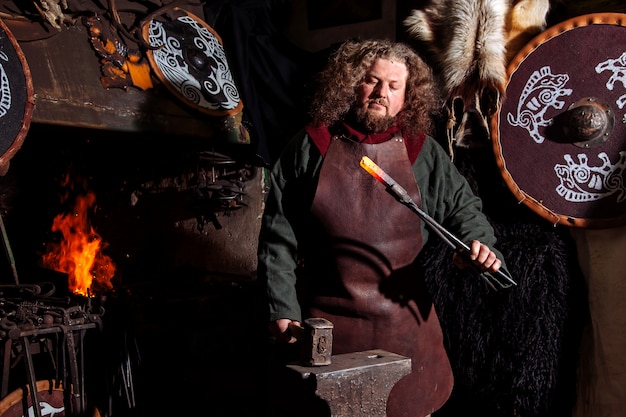 Viking blacksmith forges weapons in the old vintage forge.