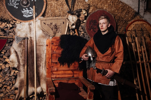 Викинг позирует на фоне древнего интерьера викингов.