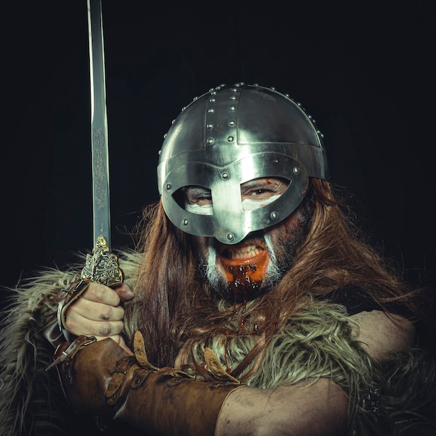 Viking, Scandinavian warrior with helmet and war paintings, wears a sword and a cape of animal skin