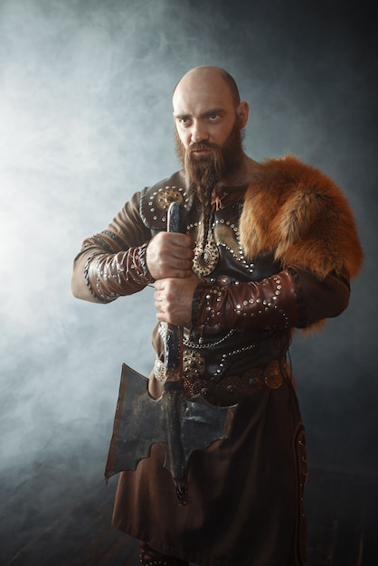 Viking with axe dressed in traditional clothes, nordic barbarian image. Ancient warrior in smoke