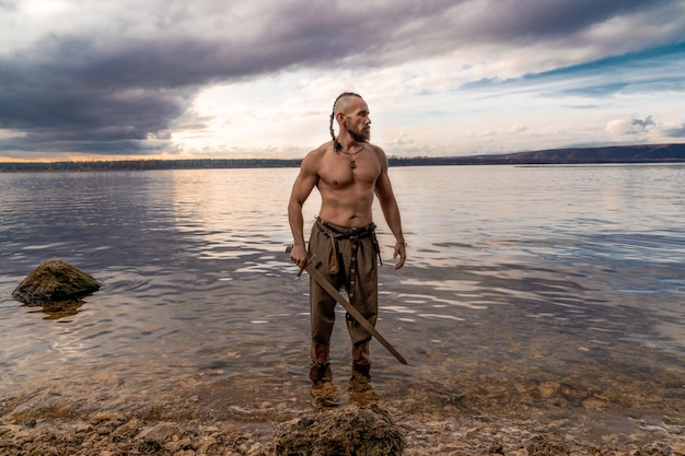 Foto vichingo con la pelle drappeggiata sulle spalle si trova sulla riva del fiume