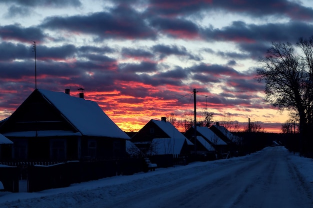 写真 村の風景 夕暮れの空に照らされた雪で覆われた村の通り