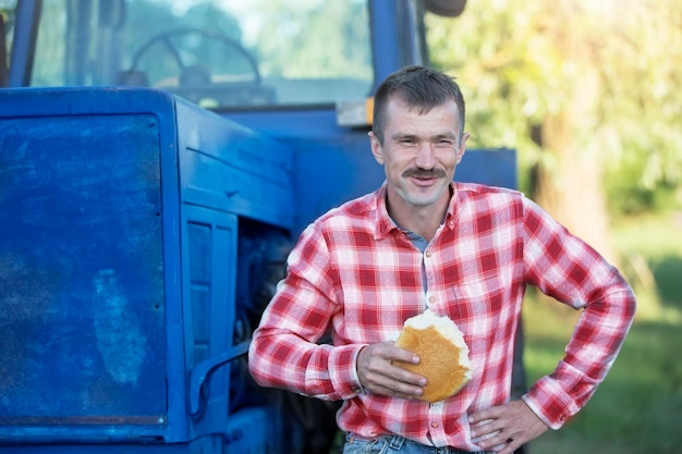 Photo the village man tractor driver is hungry and is eating a loaf