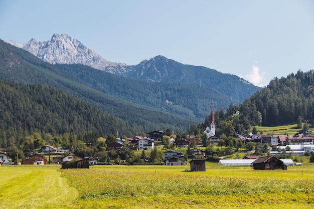 Деревня на горном лугу. Зеленый луг и горы