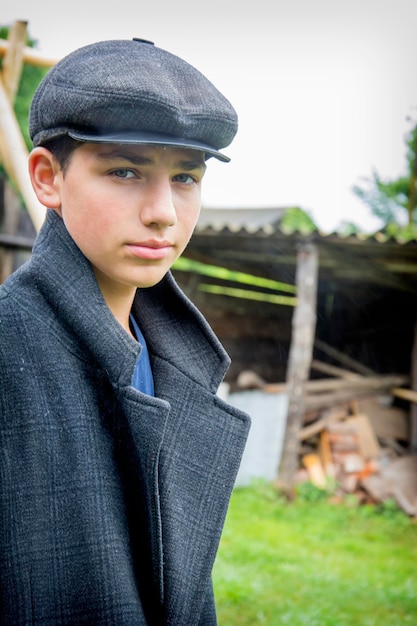 In the village on a rainy day a handsome guy in a cap and coat