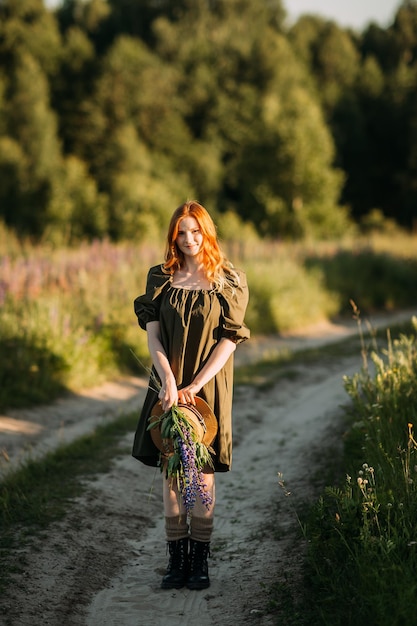 A village redhaired girl walks along a rural road in summer 3289