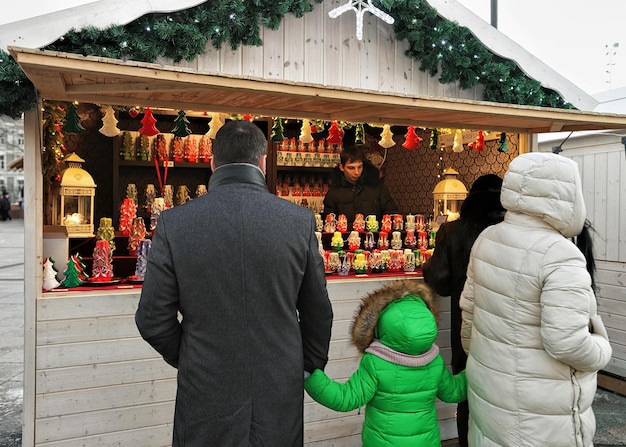 リトアニア、ビリニュス-2016年12月4日：リトアニア、ビリニュスの旧市街にあるカテドラルスクエアのクリスマスマーケットのカウンターで家族。