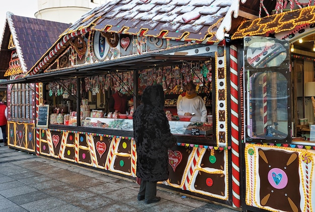 リトアニア​、​ビリニュス​-​2016​年​12​月​4​日​：​リトアニア​、​ビリニュス​、​カテドラルスクエア​の​クリスマス​マーケット​の​クリスマスキャンディーハウス​の​女性​。