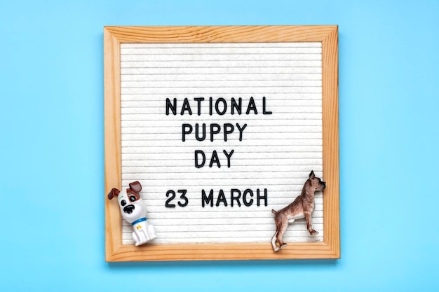 Viltbord met tekst Nationale puppydag in 23 maart schattige hondenfiguren op blauwe achtergrond