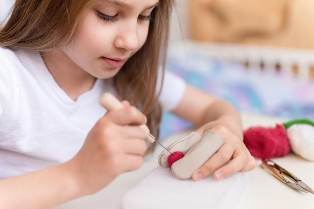 Vilten wol ambacht door handgemaakt met naald kleine jongen meisje ambachtsman negen jaar oud met de hand maakt een creatief speelgoed gemaakt van schapenhaar mensen kinderen hobby en handwerk vilten activiteit