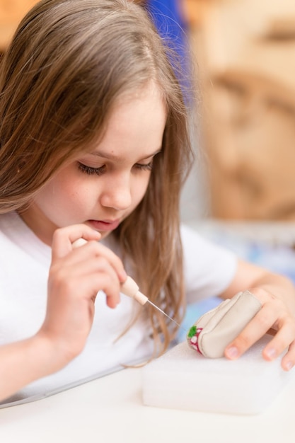 Vilten wol ambacht door handgemaakt met naald kleine jongen meisje ambachtsman negen jaar oud met de hand maakt een creatief speelgoed gemaakt van schapenhaar mensen kinderen hobby en handwerk vilten activiteit