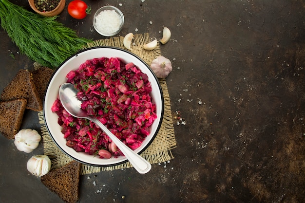 Vinaigrette met kruiden in een witte kom op een donkere achtergrond. salade van rode biet. russisch traditioneel gerecht. uitzicht van boven. vegetarisch gerecht. kopieer ruimte. voedsel achtergrond.